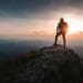 hiker standing on mountaintop at sunrise