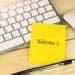 welcome written on yellow post-it note stuck to keyboard