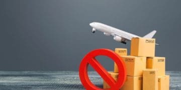 cardboard boxes and airplane lifting off with prohibited symbol on gray background