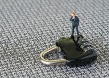 small businessman figure standing on black padlock