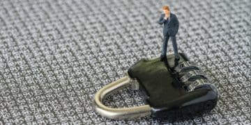 small businessman figure standing on black padlock