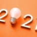 2021 with light bulb in place of zero on orange background