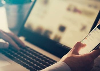 man working on smartphone and laptop