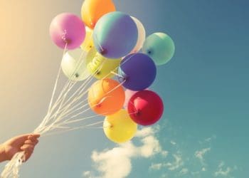hand holding multicolored balloons outside