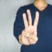 hand showing three fingers on gray background