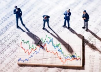 businessmen in miniature studying volatile stock market