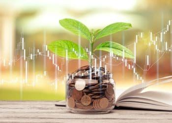 green plant growing on glass jar with coins