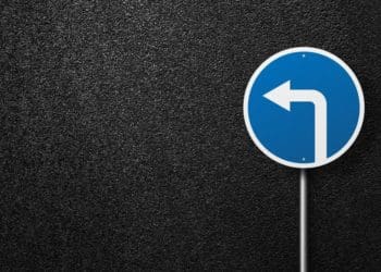 blue road sign with arrow on black asphalt background