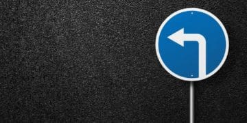 blue road sign with arrow on black asphalt background