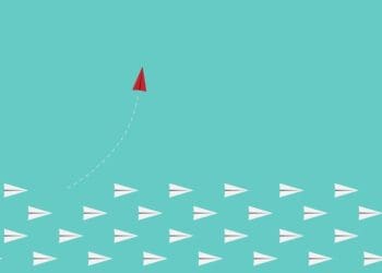 red paper plane breaking rank from white paper planes