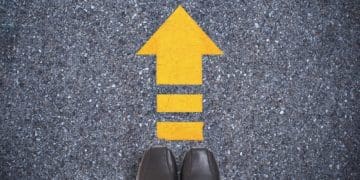 black shoes on pavement with yellow arrow pointing ahead