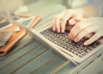 hands typing on laptop, smartphones on the table, work anywhere concept