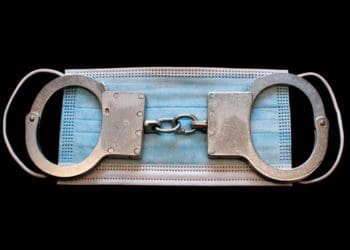 blue facemask under handcuffs on black background