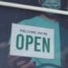 man flipping store sign to "welcome, we're open"