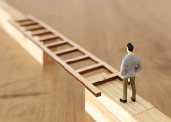 figure of man standing at ladder stretched across gap in bridge