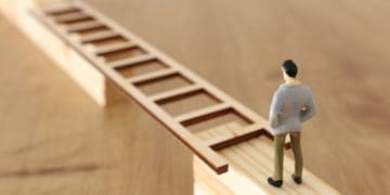 figure of man standing at ladder stretched across gap in bridge