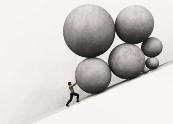 man piushing rocks uphill to symbolize burden