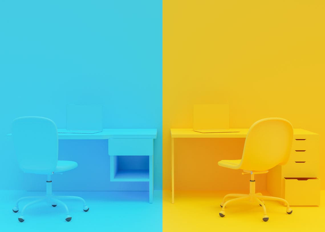 A room holds two office desks. One side is completely yellow, the other is blue.