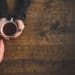 overhead shot of two people holding coffee cups as if in conversation