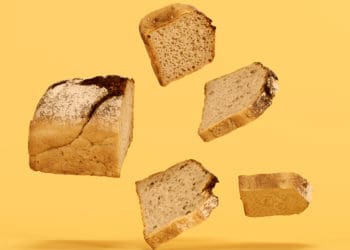 Sections of a loaf of bread are sliced and suspended in mid air before a yellow background. Delicious!