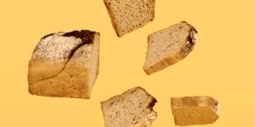Sections of a loaf of bread are sliced and suspended in mid air before a yellow background. Delicious!