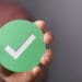 hand holding green checkmark symbol