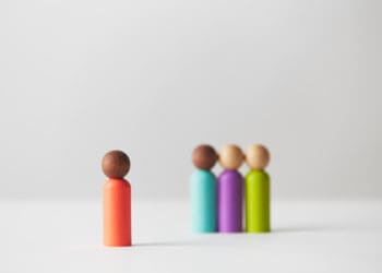 Grouped wooden figures with one isolated, symbolizing one person chosen