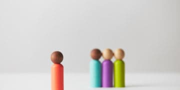 Grouped wooden figures with one isolated, symbolizing one person chosen