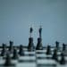 small businessmen figures shaking hands atop two chess pieces