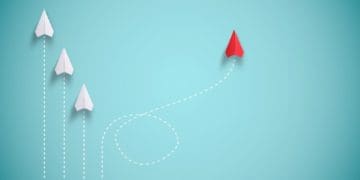 red paper plane out of line with white paper planes, concept of disruption