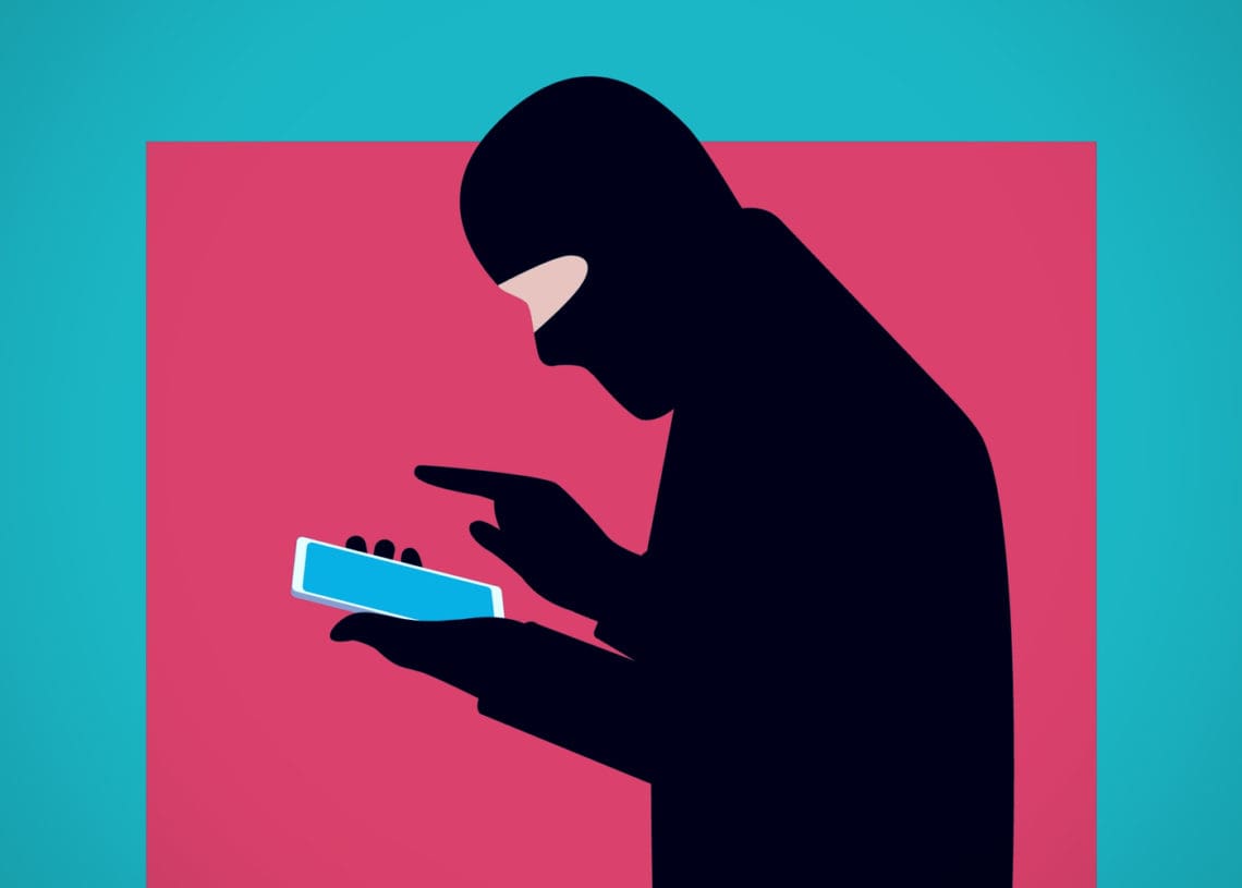 Illustration of a masked fraud actor using his smartphone.