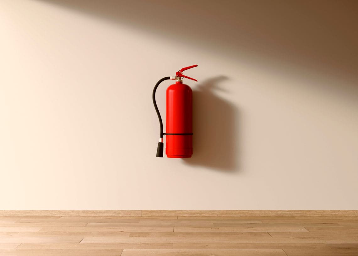 A fire extinguisher hangs on a white wall