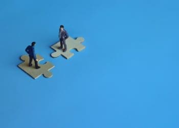 business mergers and acquisitions, partnership concept, miniature people on connecting puzzle pieces