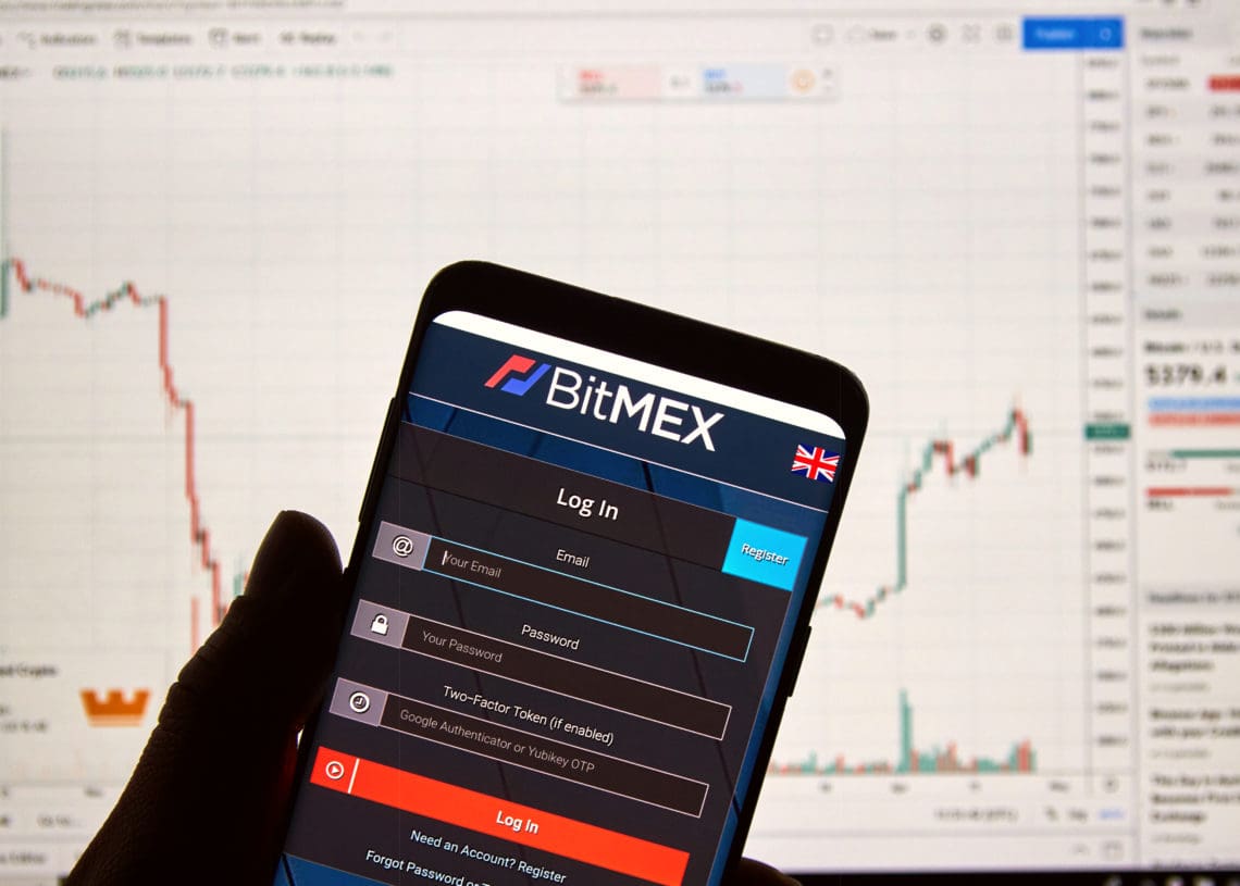 A phone displays the bitmex portal in front of a larger device.
