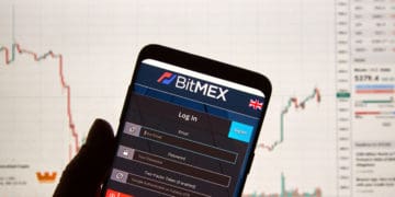 A phone displays the bitmex portal in front of a larger device.