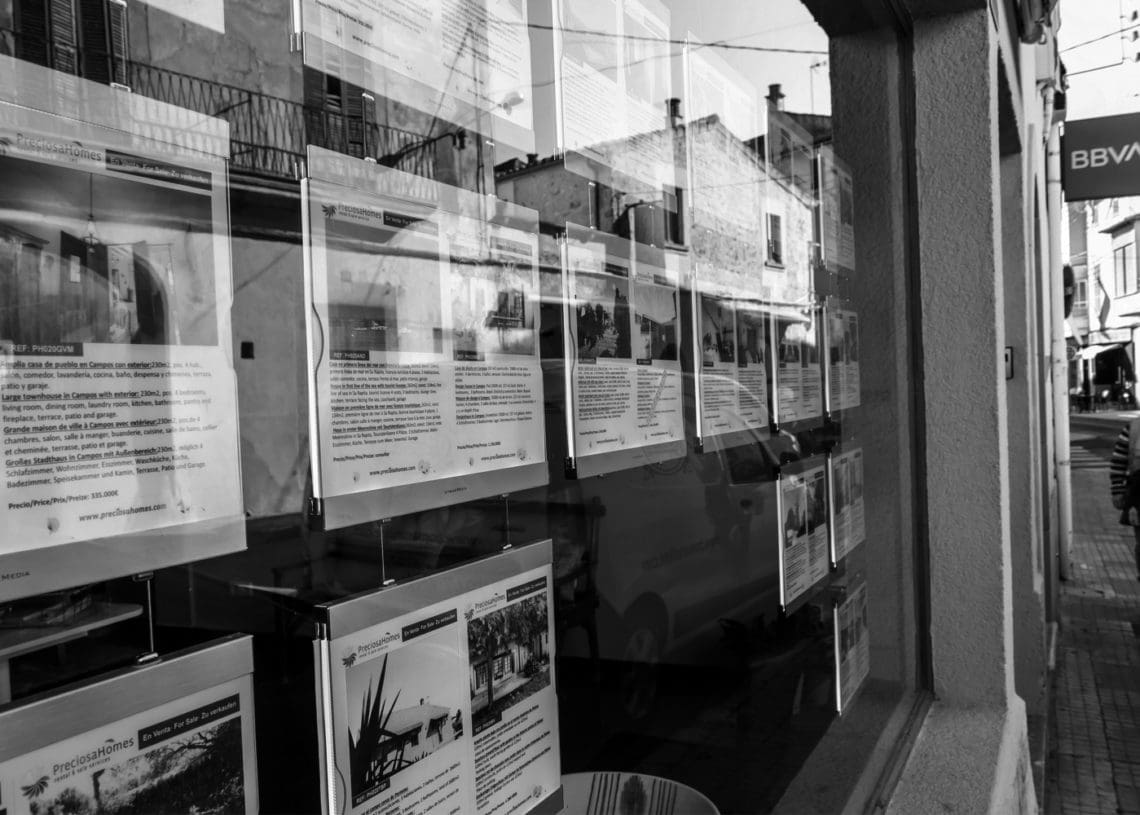 real estate listings sit in a store front window.