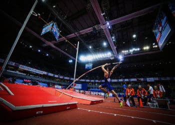 A pole vaulter takes off trying to clear a high bar