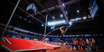 A pole vaulter takes off trying to clear a high bar