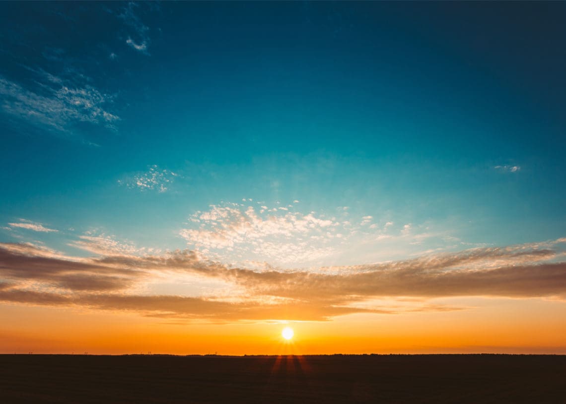 The sun is setting over fields.