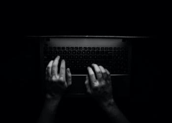 overhead b and w shot of a person's hands typing on a laptop.