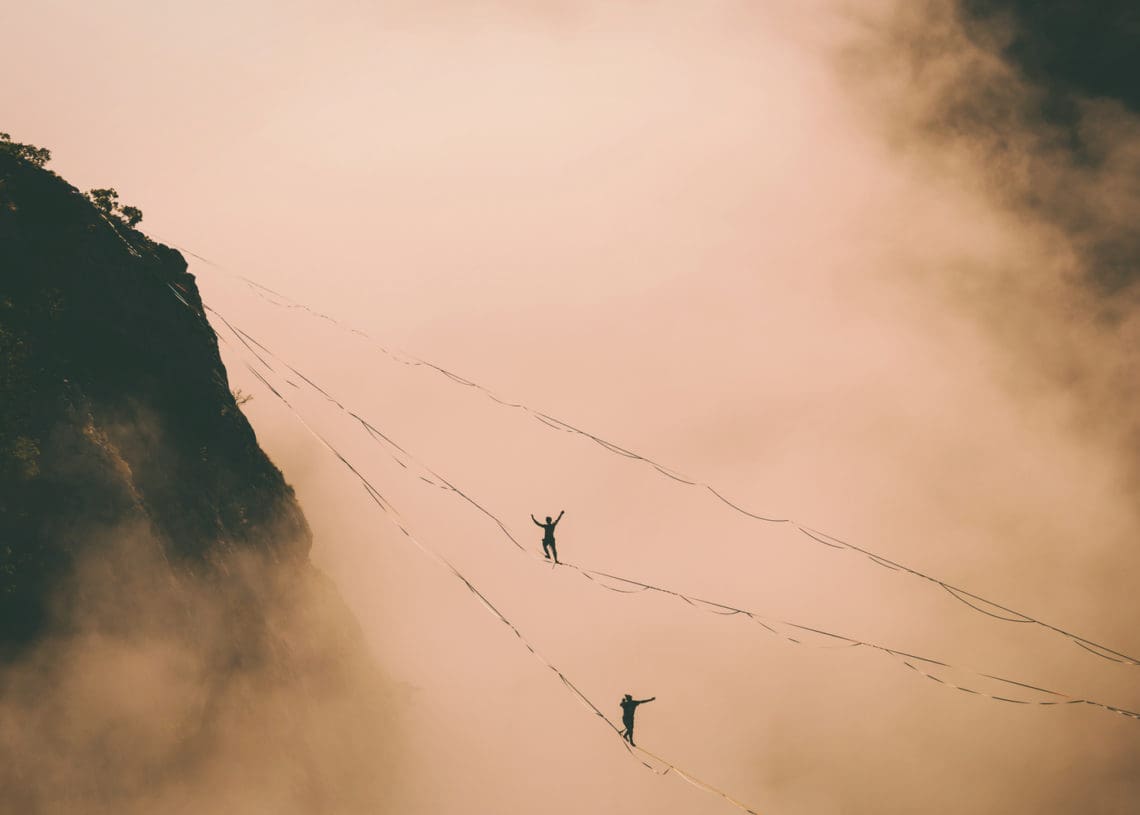 Two tightropers walk above the clouds