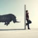 3d render of a rhino charging a closed door before which a man stands on a call