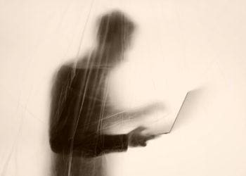 an out-of-focus cyber whistleblower obscured behind a screen