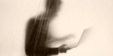 an out-of-focus cyber whistleblower obscured behind a screen