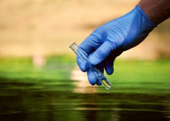 EHS compliance officer takes a water sample.