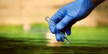 EHS compliance officer takes a water sample.