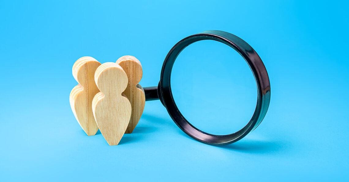 wooden people next to magnifying glass