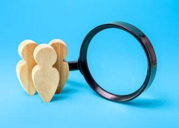 wooden people next to magnifying glass