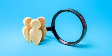 wooden people next to magnifying glass