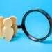 wooden people next to magnifying glass